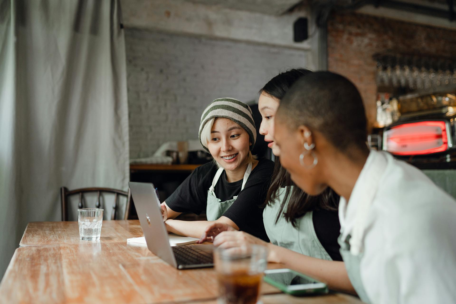 Cheerful diverse colleagues working on laptop in cafe