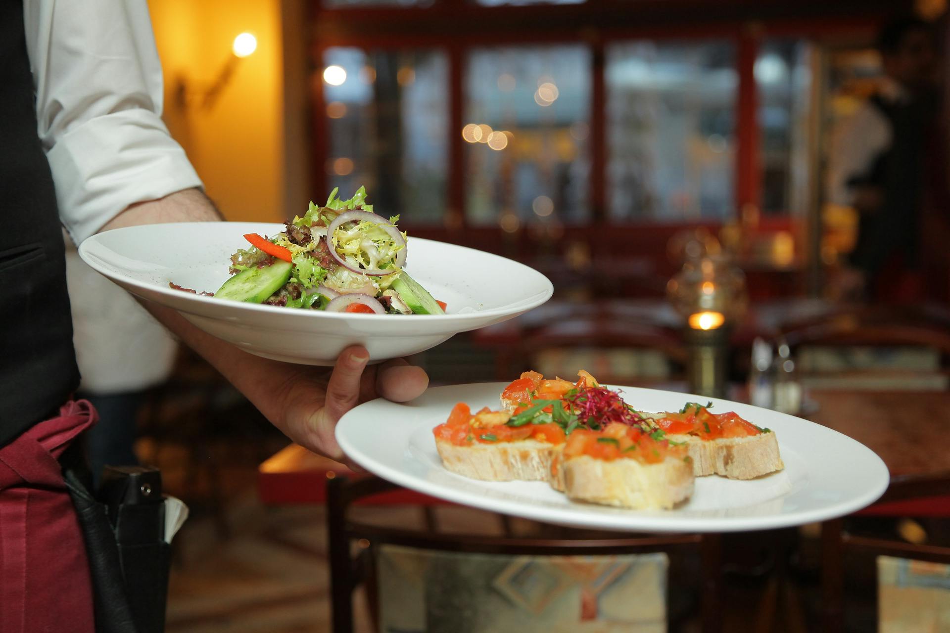 Unrecognizable man serving yummy sandwiches in diner